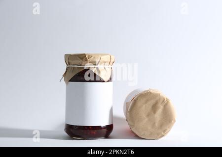 Les bocaux en verre avec la confiture de framboises sur fond blanc Banque D'Images