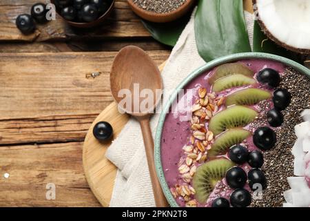 Délicieux smoothie d'acai et fruits dans un bol servi sur une table en bois, plat Banque D'Images