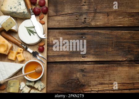 Plateau de fromages avec couteau spécialisé et fourchette sur table en bois, plat. Espace pour le texte Banque D'Images