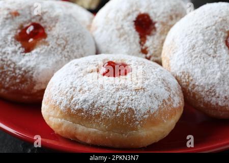 Délicieux beignets avec de la gelée et du sucre en poudre sur une assiette rouge, en gros plan Banque D'Images