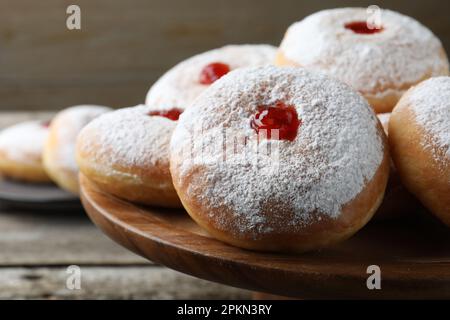 Délicieux beignets avec gelée et sucre en poudre sur un présentoir à pâtisseries en bois, gros plan Banque D'Images