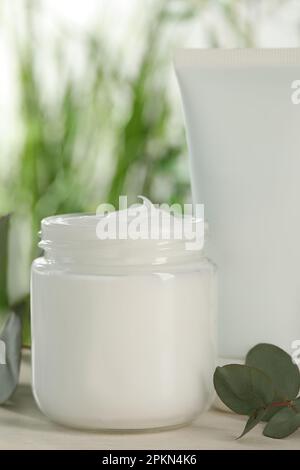 Différents produits cosmétiques de soin des mains et branches d'eucalyptus sur table en bois blanc, gros plan Banque D'Images