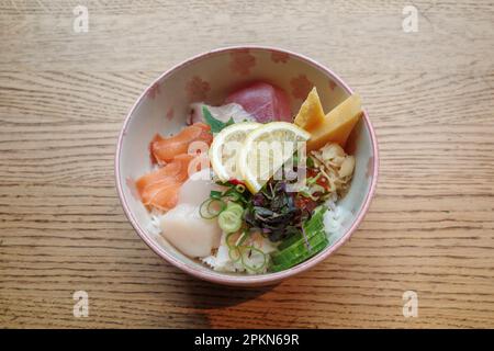 Vue de dessus de Sashimi Don, Danburi ou bol de riz japonais avec différentes tranches fraîches de poisson, crevettes, calmar, pétoncle et oeuf de tamago, sur le bois. Banque D'Images