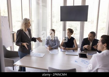 Une femme d'âge moyen confiante qui parle à divers employés Banque D'Images