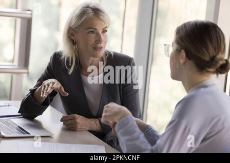 Deux jeunes et matures collègues d'affaires, des femmes qui parlent à table Banque D'Images