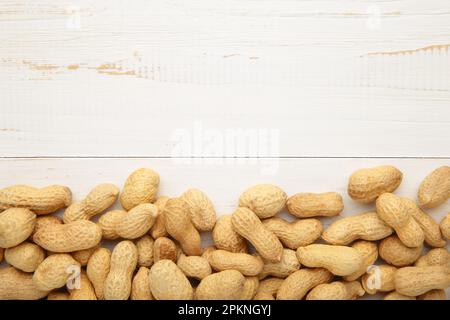 Arachides dans des coquilles sur fond blanc en bois. Vue de dessus Banque D'Images