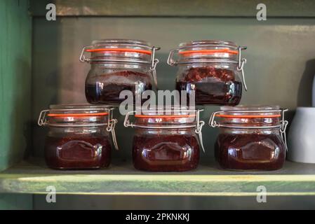 Pots avec confiture maison sur une étagère en bois dans une rangée Banque D'Images