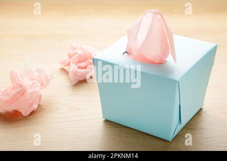 Boîte bleue avec mouchoirs en papier et serviettes froissés sur fond clair. Vue de dessus Banque D'Images