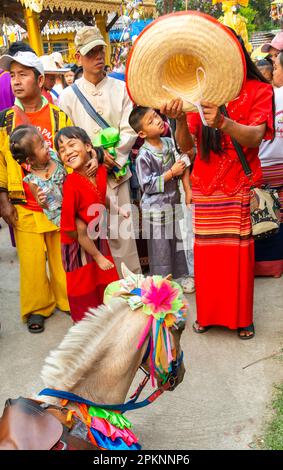 PAI,Nord de la Thaïlande-4 avril 2023: Une foule regarde sur, comme un cheval vêtu de la guirlande cérémonielle s'effondre, et est aidé par une femme, qui utilise son grand ha Banque D'Images