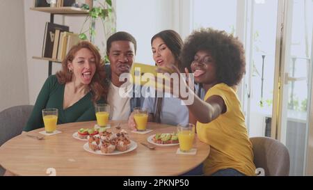 Amis multiethniques s'amuser tout en prenant un selfie pendant le petit déjeuner Banque D'Images