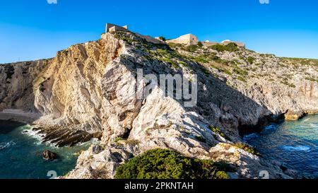 Un panorama époustouflant présente le terrain érodé et la beauté rugueuse d'une falaise, avec les ruines du fort Fortaleza de Belixe perchées au sommet. Banque D'Images