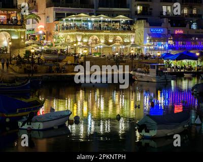 St Julian, Malte - Mai, 2021: La baie de Spinola avec beaucoup de bateaux colorés en face de célèbres restaurants touristiques pendant la nuit. Europe Banque D'Images