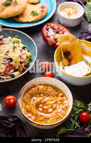 Tableau servi avec des plats végétariens traditionnels du Moyen-Orient. L'hoummos, tahini, pitta, salade de couscous et le babeurre tremper avec de l'huile d'olive. Le dîner de travail Banque D'Images