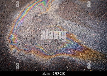 Fuite d'huile ou d'essence d'une voiture sur l'asphalte humide par une journée ensoleillée. Arrière-plan abstrait. Banque D'Images