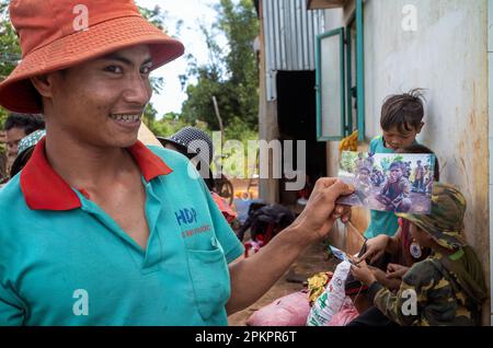 Un jeune homme minoritaire ethnique de Jerai dans les Highlands centraux du Vietnam tient une photo de son père fumant une cigarette en tant que jeune garçon 30 ans plus tôt. Banque D'Images