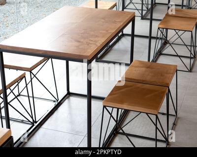 Table en bois vide avec chaises sur carreaux de ciment arrière-plan sans personne, style loft intérieur de café. Mobilier en bois vide avec acier noir Banque D'Images