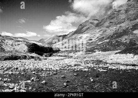 Un des nombreux ruisseaux de montagne qui s'écoulent à travers le paysage accidenté de Glen COE, dans les Highlands écossais, en noir et blanc Banque D'Images