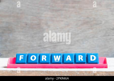 Lettre de l'alphabet avec le mot vers l'avant dans un rack de couleur rouge sur fond de bois Banque D'Images