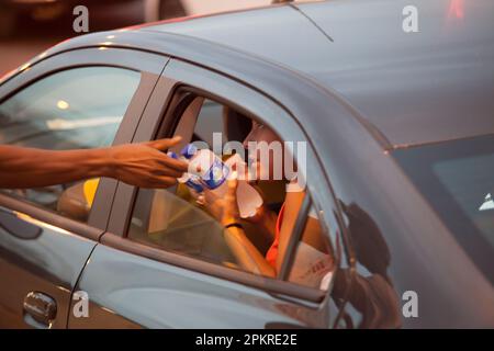 Les habitants de Complexo da Mare, un réseau massif de favelas qui se trouve le long de la Linha Vermelha (ligne rouge), la principale autoroute de l'aéroport international de Rio de Janeiro au centre-ville, travaillent comme vendeurs de rue pendant les heures de pointe à l'expreessway - famiy achète l'eau minérale. Banque D'Images