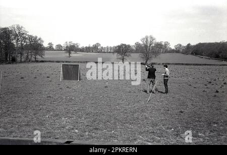 Années 1960, historique à l'extérieur dans un champ, deux hommes, pratique de tir ou peut-être faisans Angleterre, Royaume-Uni. Banque D'Images