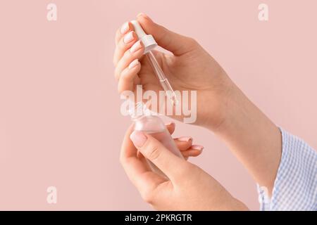 Femme avec une bouteille d'huile de cuticule près du mur de couleur Banque D'Images