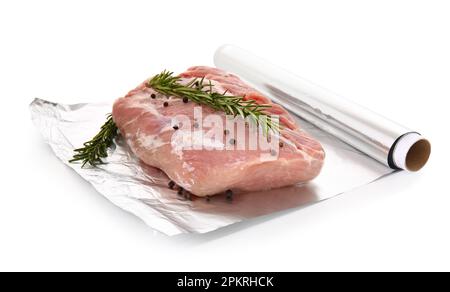 Rouleau de papier d'aluminium avec morceau de viande crue, romarin et grains de poivre sur fond blanc Banque D'Images