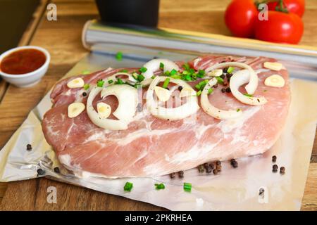 Rouleau de papier d'aluminium avec morceau de viande crue et d'épices sur table en bois, gros plan Banque D'Images