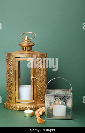 Lampes musulmanes avec bougies allumées et perles de prière sur fond vert Banque D'Images