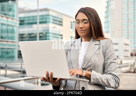 Femme d'affaires afro-américaine prospère utilisant un ordinateur portable à l'extérieur de la rue. Banque D'Images