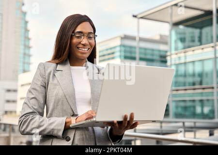 Femme d'âge moyen utilisant l'écran tactile de l'ordinateur portable se tenant près du centre de bureau. Banque D'Images