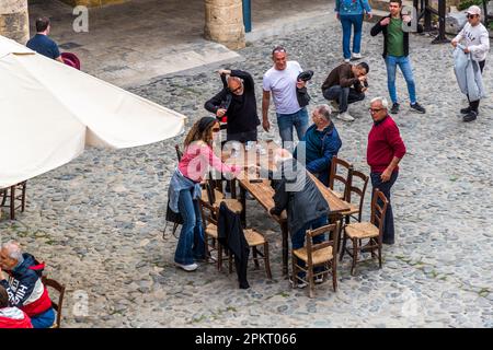 Plusieurs membres du Coffee Club bi-communautaire se saluent d'une poignée de main à une table dans la cour du Büyük Han à Lefkoşa/Nicosia, République turque de Chypre du Nord (RTNC). Cette caravanserail historique est l'une des principales attractions touristiques de Nicosie, mais malgré sa popularité auprès des voyageurs, elle est également fréquentée par de nombreux habitants locaux. Les cafés et restaurants occupent le rez-de-chaussée du complexe presque carré à deux étages, avec des boutiques de souvenirs et de l'artisanat au premier étage. Banque D'Images