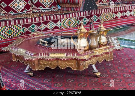 Cruches de café arabe traditionnel ou qahwa à Dubaï avec table et canapé sur tapis oriental avec des charbons chauds Banque D'Images