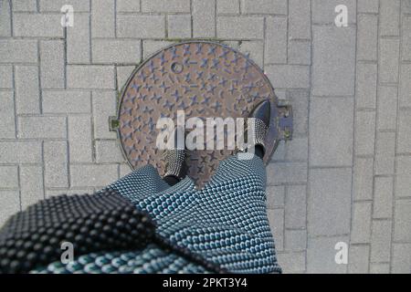 Femme en jupe à motifs midi et bottes de cowboy cloutées noires sur la rue pavée, vue de dessus Banque D'Images