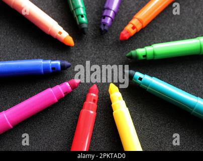 Marqueurs multicolores disposés en cercle isolé sur la vue d'angle noire Banque D'Images