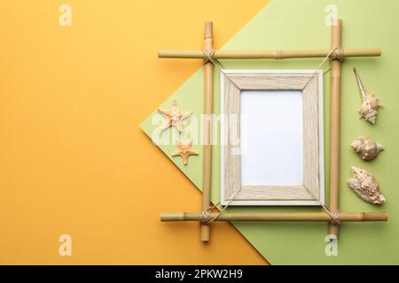 Cadre en bambou vide, étoiles de mer et coquillages sur fond de couleur, plat. Espace pour le texte Banque D'Images