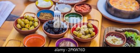 BANNIÈRE, TABLE de petit-déjeuner turque DE FORMAT LONG. Pâtisseries, légumes, légumes verts, olives, fromages, oeufs frits, épices, confitures, miel, thé dans la marmite de cuivre et Banque D'Images