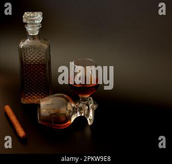 Cigare cubain, carafe en cristal et deux verres de whisky sur fond noir. Gros plan. Banque D'Images