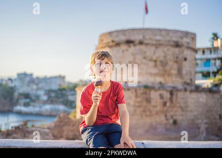 Garçon touriste manger de la glace turque sur fond de la Tour Hidirlik à Antalya avec la toile de fond de la baie méditerranéenne de l'ancien Kaleici Banque D'Images