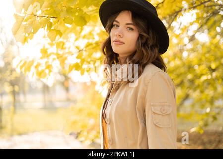 Portrait en gros plan d'une femme gaie en chapeau sur un arrière-plan flou de parc d'automne. Photo de fille à la mode avec de beaux cheveux bruns souriant à l'appareil photo. Copier Banque D'Images