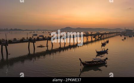 Vue aérienne des bateaux de pêche sur la plage à l'embarcadère de Chalong au lever du soleil. Lever de soleil avec des rayons de lumière jaune doux et d'autres effets atmosphériques. coloré Banque D'Images