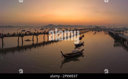 Vue aérienne des bateaux de pêche sur la plage à l'embarcadère de Chalong au lever du soleil. Lever de soleil avec des rayons de lumière jaune doux et d'autres effets atmosphériques. coloré Banque D'Images