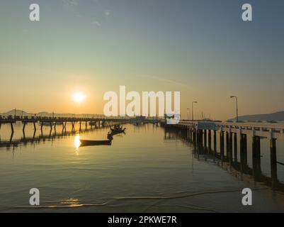 Vue aérienne des bateaux de pêche sur la plage à l'embarcadère de Chalong au lever du soleil. Lever de soleil avec des rayons de lumière jaune doux et d'autres effets atmosphériques. coloré Banque D'Images