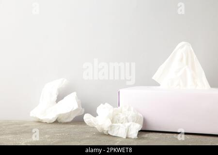 Boîte avec mouchoirs en papier et serviettes froissés sur fond gris. Vue de dessus Banque D'Images