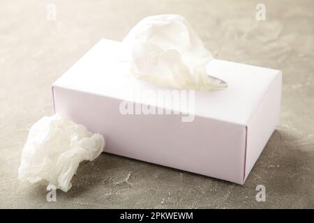 Boîte avec mouchoirs en papier et serviettes froissés sur fond gris. Vue de dessus Banque D'Images