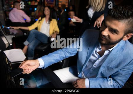 Main de joueur masculin tenir la carte de crédit prêt à gagner le jeu dans la machine à sous de jeu de casino Banque D'Images