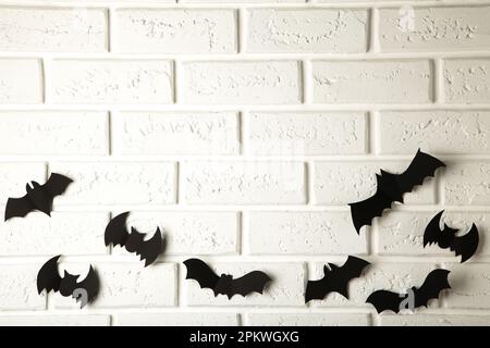 Halloween, décoration et concept effrayant - des chauves-souris en papier noir survolant un fond blanc Banque D'Images