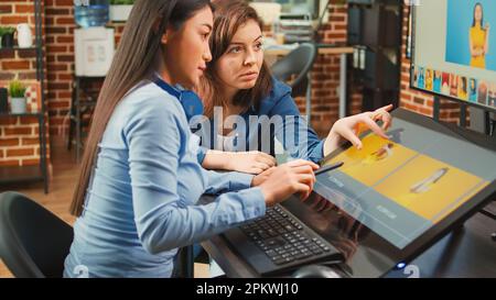 Une équipe de photographes travaillant sur le montage de photos avec un écran tactile, utilisant un stylet sur une tablette graphique. Femmes éditeurs retouche des photos professionnelles avec le calibrage des couleurs, la production multimédia. Banque D'Images