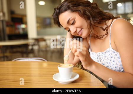 Femme sincère qui agite un café assis dans un restaurant Banque D'Images