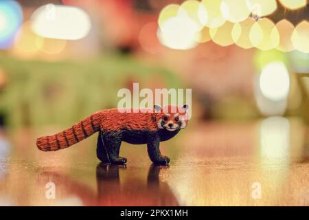 Animal jouet panda rouge dans une pièce sombre sur une table avec fond bokeh Banque D'Images