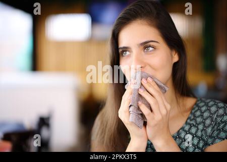 Femme qui nettoie la bouche avec une serviette dans un restaurant qui donne sur l'extérieur Banque D'Images